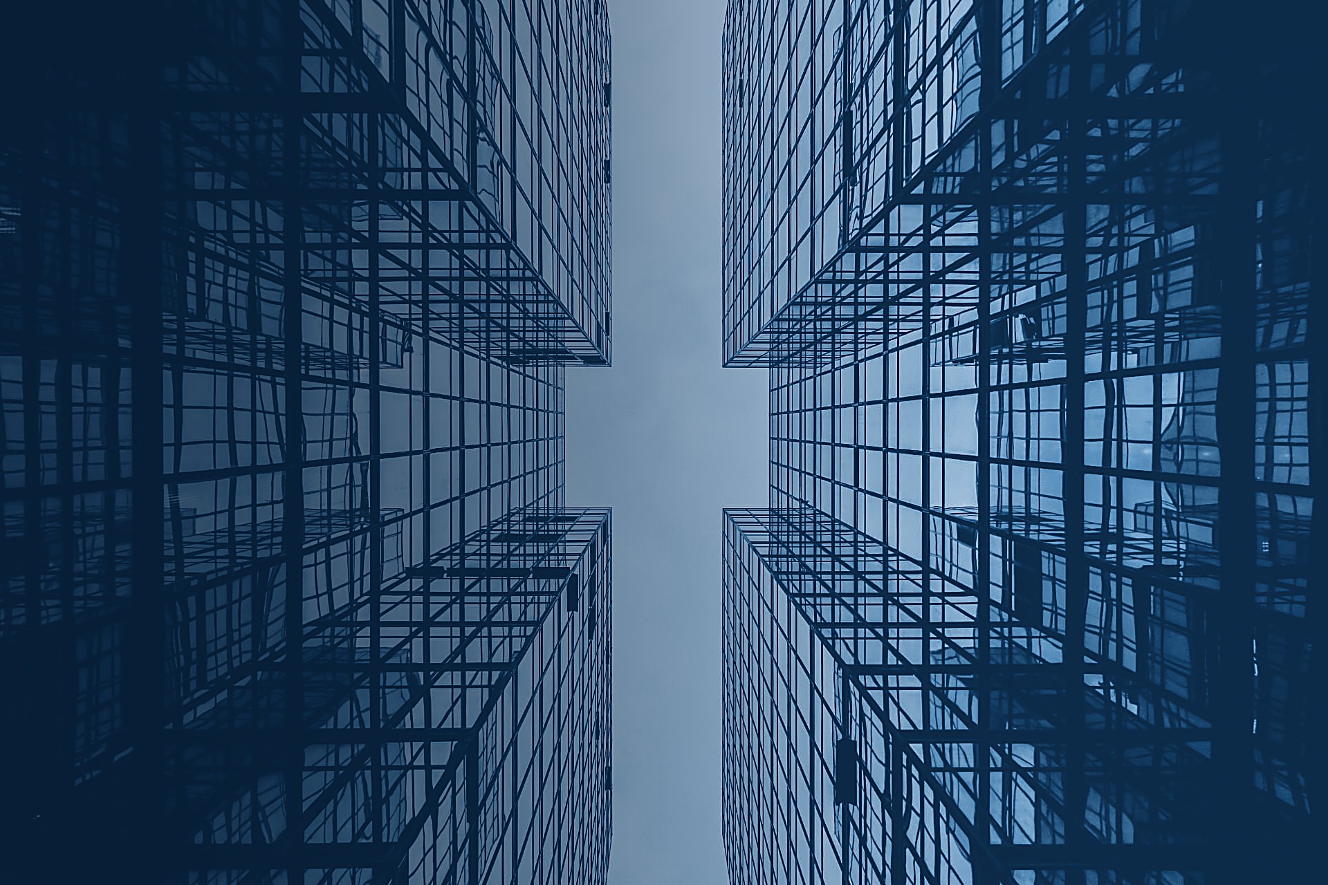 Looking up between amber-lit glass towers towards a bright gap of sky